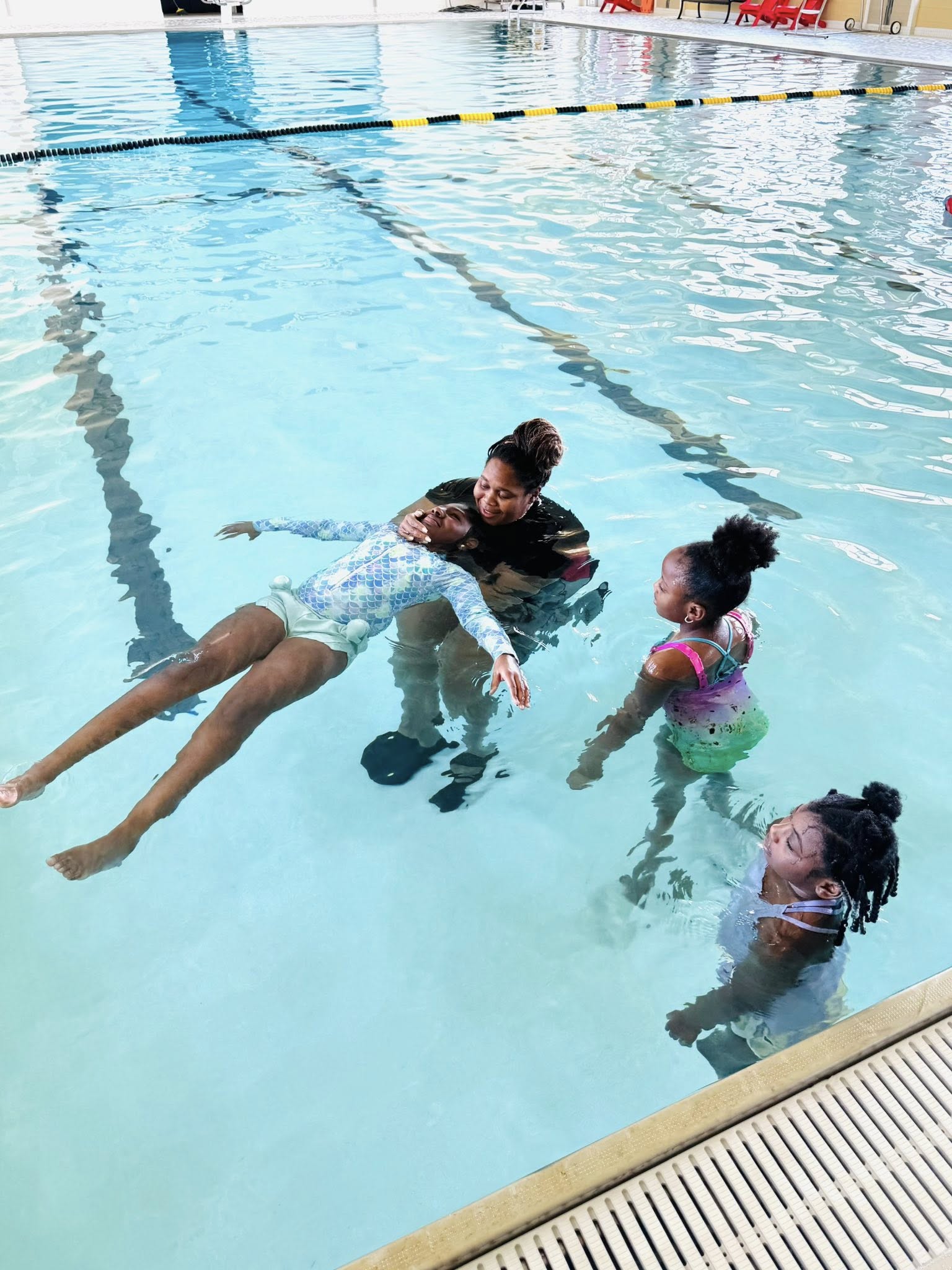 A woman helping a girl float in a pool.